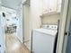 Hallway laundry closet with a white washing machine and overhead cabinets for storage at 207 Blackburn Blvd, North Port, FL 34287