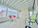 Enclosed porch with white wicker furniture, red throw pillows, and view of an American flag at 207 Blackburn Blvd, North Port, FL 34287