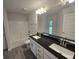Bright bathroom with double sink vanity featuring black countertops and a shower over bath at 14146 Baracoa Ln, Port Charlotte, FL 33981