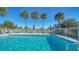 Community pool with surrounding patio furniture and lush tropical landscaping at 1452 San Cristobal Ave # B103, Punta Gorda, FL 33983