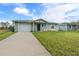 Newly built home with a gray exterior, white garage door, and grassy lawn at 27130 Savoy Dr, Punta Gorda, FL 33955