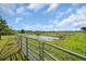 Open farmland with a tranquil pond and fence at 15871 Huffmaster Rd, North Fort Myers, FL 33917