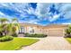 Tan one-story house with a three-car garage, lush landscaping, and a paved driveway at 3112 Tripoli Blvd, Punta Gorda, FL 33950
