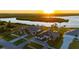 Aerial view of beautiful homes with well-kept lawns, white fences, and stunning waterfront access at sunrise at 5117 Collingswood Blvd, Port Charlotte, FL 33948