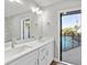 Bright bathroom with double sinks, a large mirror, and access to the pool area at 7359 Van Lake Dr, Englewood, FL 34224