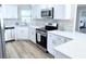 Well-lit kitchen showcasing stainless steel appliances, white cabinets, quartz countertops, and hardwood floors at 7359 Van Lake Dr, Englewood, FL 34224