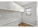 Well-lit laundry room with white cabinets, countertop, and accenting stone backsplash at 7359 Van Lake Dr, Englewood, FL 34224