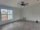 Spacious living room with wood-look tile flooring, large windows, and a ceiling fan at 13541 Jeronimo Ln, Port Charlotte, FL 33981