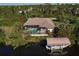 Aerial view of home with screened pool, private dock, boat lift, and lush surrounding landscape at 15600 Aldama Cir, Port Charlotte, FL 33981