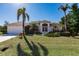 Charming home with a manicured front lawn, mature palm trees, and a well-maintained exterior at 15600 Aldama Cir, Port Charlotte, FL 33981