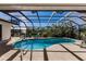 A screened-in pool area featuring clear blue water, lounge chairs, and views of the surrounding greenery at 15600 Aldama Cir, Port Charlotte, FL 33981