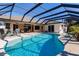 Inviting pool area with screened enclosure, patio furniture, and lush landscaping at 15600 Aldama Cir, Port Charlotte, FL 33981
