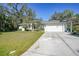 Landscaped yard, driveway, and a single-story house with white exterior and attached garage at 17080 Kellog Ave, Port Charlotte, FL 33954