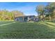 Spacious backyard with lush green grass, leading up to the home with a screened-in lanai at 5344 Swaying Palm Dr, Punta Gorda, FL 33982