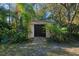 White storage shed with dark brown double doors nestled in tropical landscaping at 6405 Buckboard St, North Port, FL 34291