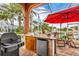 Outdoor kitchen with grill, mini-fridge, and seating area at 108 Roselle Ct, Port Charlotte, FL 33952