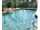 Sparkling in-ground pool with waterfall feature and screened enclosure overlooking lush landscaping at 1196 Hinton St, Port Charlotte, FL 33952
