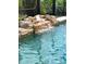 Close up of sparkling in-ground pool with serene waterfall feature and lush landscaping at 1196 Hinton St, Port Charlotte, FL 33952