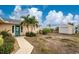 Charming home exterior with colorful door, mature landscaping, and a detached garage, all with a glimpse of the water at 3220 Peace River Dr, Punta Gorda, FL 33983
