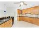 Well-lit kitchen with black countertops, wooden cabinets, and stainless steel appliances with tile flooring at 3220 Peace River Dr, Punta Gorda, FL 33983