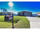 Charming home featuring a mailbox, expansive lawn, concrete driveway, and stone accents near the entryway at 3393 Kacher Rd, North Port, FL 34288