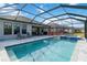 Inviting pool area featuring a screened enclosure, patio furniture, and a spa at 5640 Blue Reef Pl, Nokomis, FL 34275