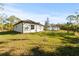 Rear view of a house with a grassy yard and another house in the distance at 14059 Gailwood Ave, Port Charlotte, FL 33953