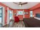 Bright bedroom with warm walls, ceiling fan, accent wall, wood-look floors, and glass paneled doors at 19983 Midway Blvd, Port Charlotte, FL 33948