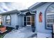 Inviting entrance of blue single-Gathering home featuring arched windows, a screened porch, and manicured landscaping at 19983 Midway Blvd, Port Charlotte, FL 33948