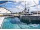 Stunning screened-in pool with sleek lounge chairs, waterfall feature, and a clear, refreshing water at 19983 Midway Blvd, Port Charlotte, FL 33948
