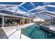 Screened-in pool area with a covered lounge space, patio seating, and solar panels on the roof at 19983 Midway Blvd, Port Charlotte, FL 33948
