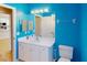 Bright blue bathroom featuring a vanity with a large mirror and a toilet, with an adjacent doorway at 3097 Royal Palm Dr, North Port, FL 34288