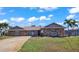 Tan house with stone accents, a spacious driveway, and palm trees in the front yard at 3310 Middletown St, Port Charlotte, FL 33952