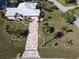 Aerial view of a light pink home with a beautiful driveway, lush landscaping, and well-manicured lawn at 649 Maltese Dr, Punta Gorda, FL 33950