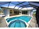 Screened in pool with hot tub and white stone patio with covered porch and outdoor kitchen at 649 Maltese Dr, Punta Gorda, FL 33950