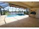 Screened in pool with hot tub and white stone patio with covered porch and outdoor kitchen overlooking a lake at 649 Maltese Dr, Punta Gorda, FL 33950