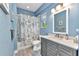 Bathroom with gray vanity, white countertop, toilet and bath-shower combo with blue textured walls at 1205 Bartlett Ave, North Port, FL 34288
