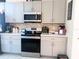 Modern kitchen features stainless steel appliances, gray cabinets, and a stylish backsplash at 18043 Avonsdale Cir, Port Charlotte, FL 33948