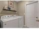 Functional laundry room with white washer and dryer and decorative shelving at 18043 Avonsdale Cir, Port Charlotte, FL 33948