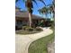 Community clubhouse featuring mature palm trees, benches, and a curved sidewalk on a clear sunny day at 2023 Lynx Run, North Port, FL 34288