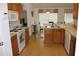 Eat-in kitchen with wood cabinets, white appliances, and breakfast bar at 4692 Hillman Ter, North Port, FL 34288