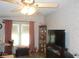 Bright living room with large windows, ceiling fan, and flat-screen TV at 6546 Greenview Ct, North Port, FL 34287