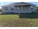 The home's backyard has a covered porch, a lawn, and natural surroundings at 13480 Allentown Ave, Port Charlotte, FL 33981