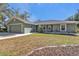Green house exterior with a two-car garage and a spacious front yard at 1811 Music Ln, North Port, FL 34286
