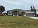 Charming single-Gathering home with gray exterior, arched windows, well-maintained lawn and two-car garage at 233 W Pine Valley Ln, Rotonda West, FL 33947