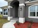 Beautiful entryway features an arched front porch, decorative lighting, and tidy landscaping at 233 W Pine Valley Ln, Rotonda West, FL 33947