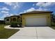 Front exterior shot of a well-maintained yellow house with a two-car garage and a long driveway at 25115 Esmeralda Ct, Punta Gorda, FL 33955