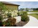 Closeup of the landscaped front yard including a sidewalk, decorative rocks, flowers, and bushes at 25115 Esmeralda Ct, Punta Gorda, FL 33955