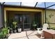 Relaxing screened-in patio with brick flooring, potted plants, and comfortable seating arrangement at 25115 Esmeralda Ct, Punta Gorda, FL 33955