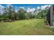 Spacious backyard with a large grassy area, mature trees, and a peaceful waterfront view at 27545 Monte Cristo Blvd, Punta Gorda, FL 33955